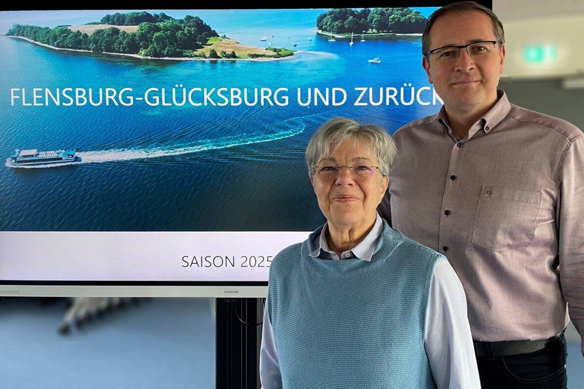 eine Frau und ein Mann stehen neben einem großen Bildschirm