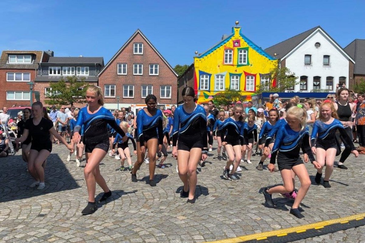 Eine Gruppe bewegt sich in Sportbekleidung auf einem Platz.