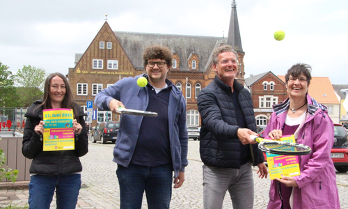 Zwei Frauen und zwei Männer stehen auf dem Marktrplatz in Bredstedt, halten Veranstaltungsplakate und Tennisschläger in Händen.