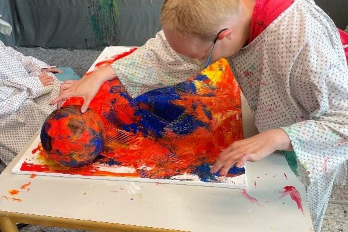 ein Künstler beugt sich über eine Leinwand, die vor ihm liegt.