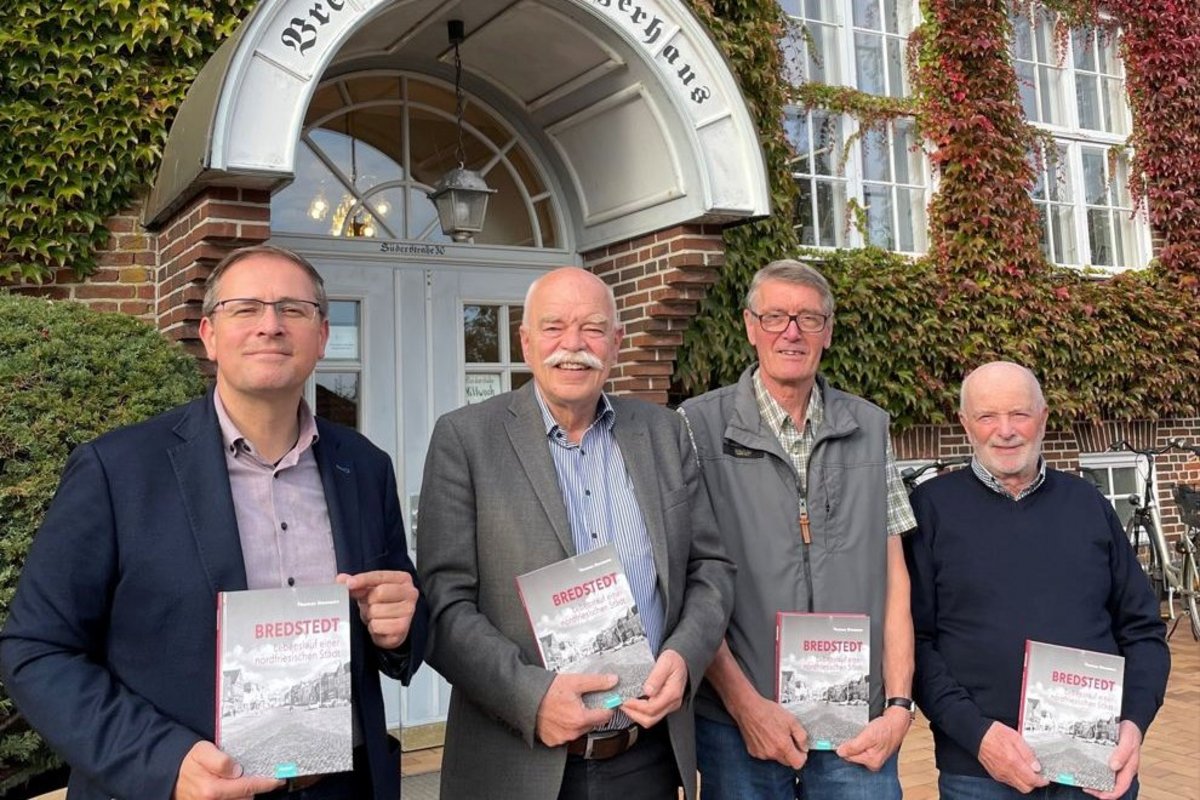 Vier Männer stehen nebeneinander und halten jeweils ein Buch