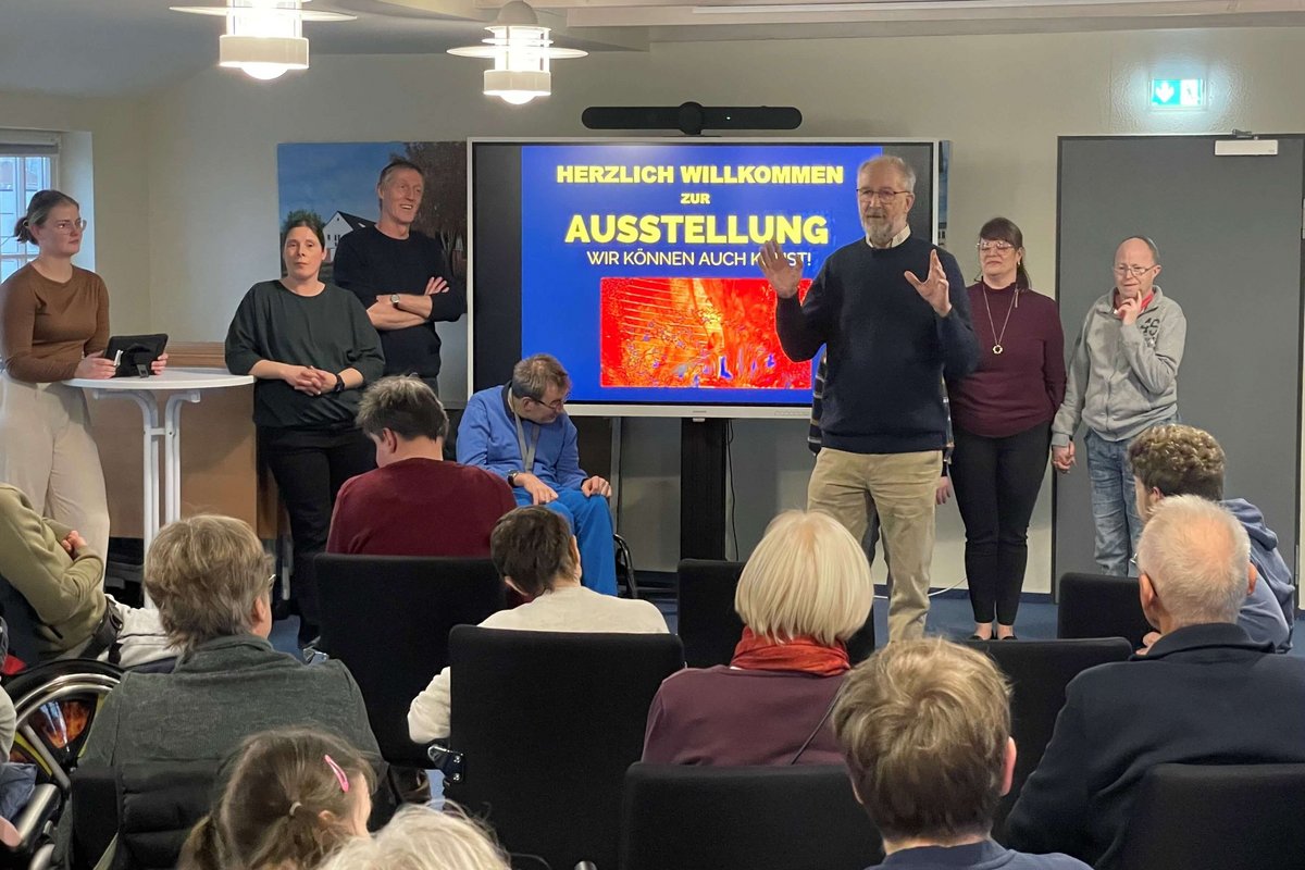 Mehrere Menschen stehen vor einer Gruppe sitzender Menschen