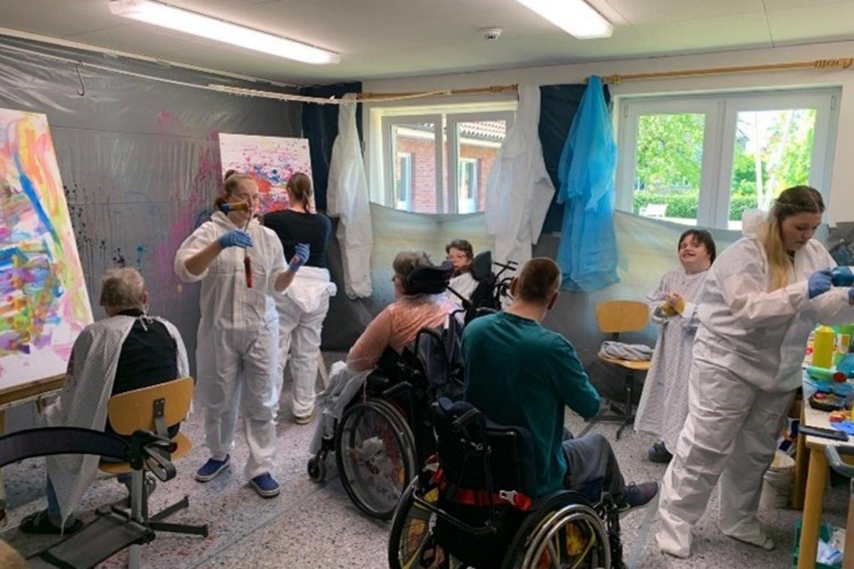 Menschen in Rollstühlen und ohne agieren in einem Raum 