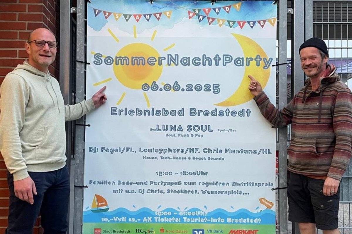 Zwei Männer stehen neben einem großen Plakat