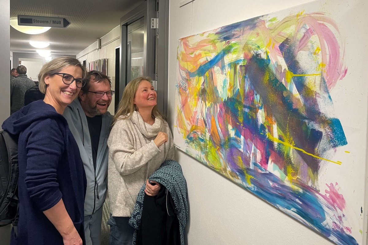 Drei Menschen betrachten ein buntes Bild