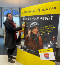 Elisabeth Rotte steht vor einem großen Werbebanner der Kampagne "Winterhelden".