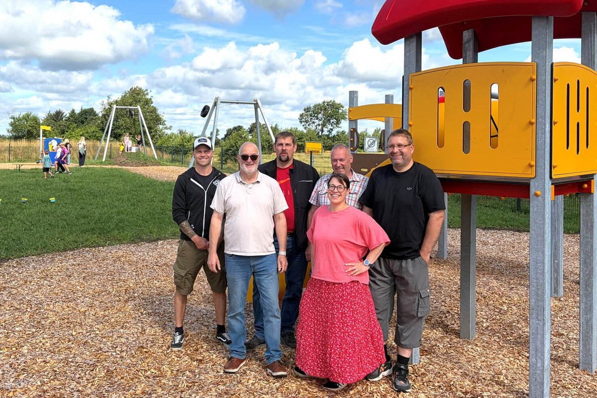 Mitglieder der Gemeindevertretung Goldebeks freuen sich über den neuen Spielplatz: Timo Jensen (von links), Bürgermeister Peter Jessen, Stefan Christiansen, Catharina Tudsen, Hauke Jensen und Reiner Bakker. Foto: Felix Middendorf Fünf Männer und eine Frau stehen vor einem großen Spielgerät. Im Hintergrund spielen Kinder.