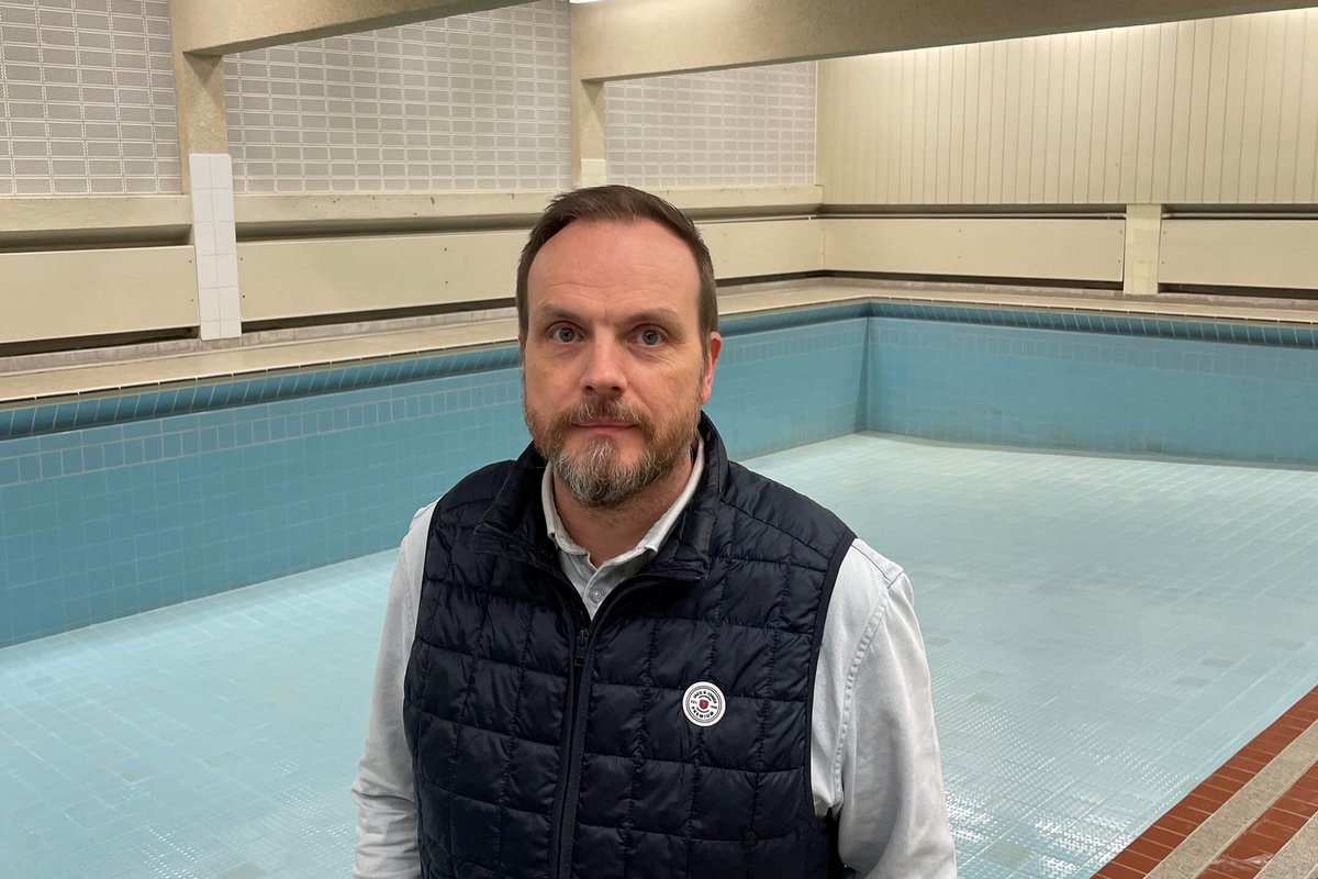 Ein Mann steht vor einem leeren Schwimmbecken