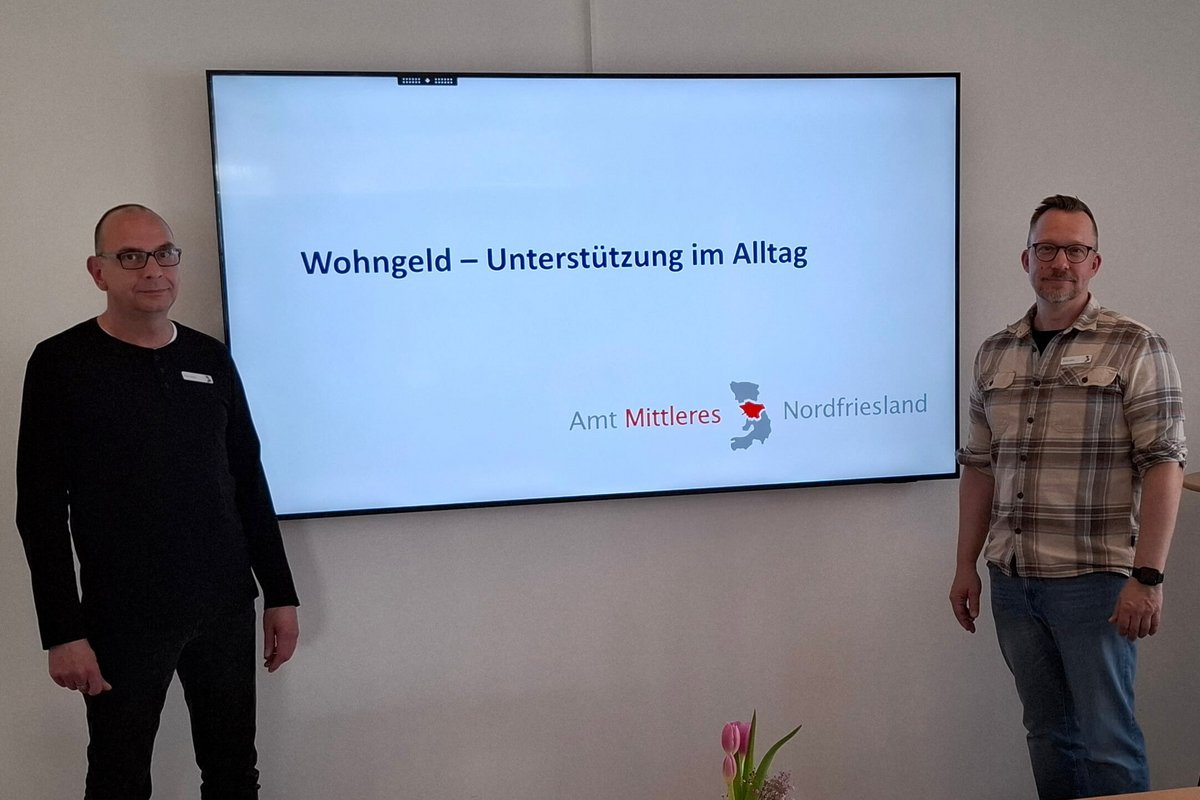 Zwei Männer stehen neben einem großen Bildschirm